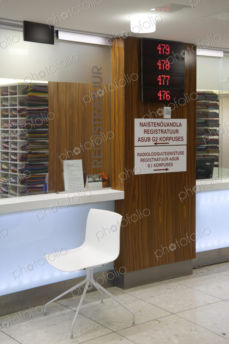 Waiting area and reception desk at a modern hospital, with signs and electronic display