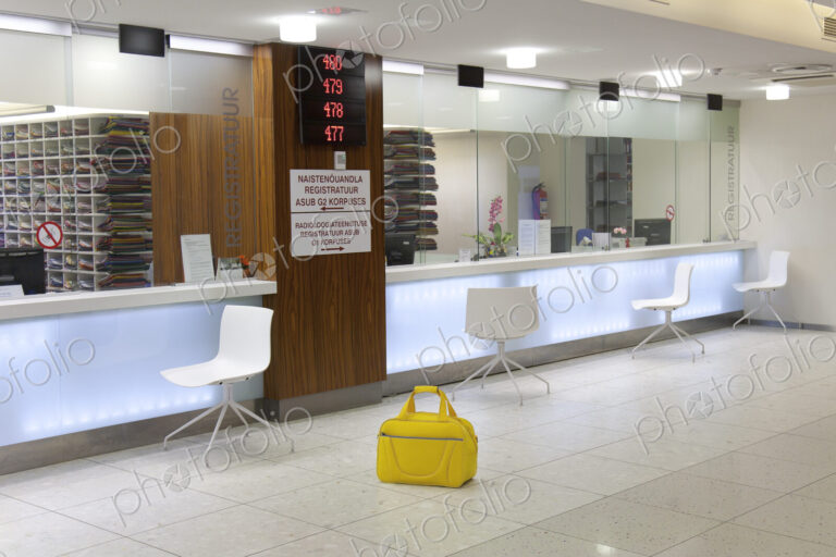 Waiting area and reception desk at a modern hospital, with signs and electronic…