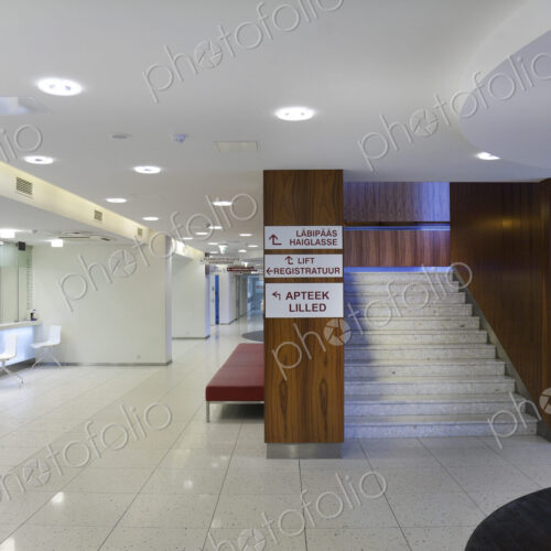 Waiting area and reception desk at a modern hospital, with signs and stairs Waiting area and reception desk at a modern hospital, with signs and stairs