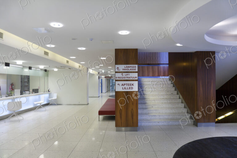 Waiting area and reception desk at a modern hospital, with signs and stairs