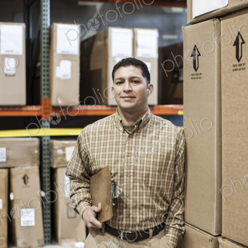 Warehouse worker among racks of boxed products in a distribution warehouse. Warehouse worker among racks of boxed products in a distribution warehouse.