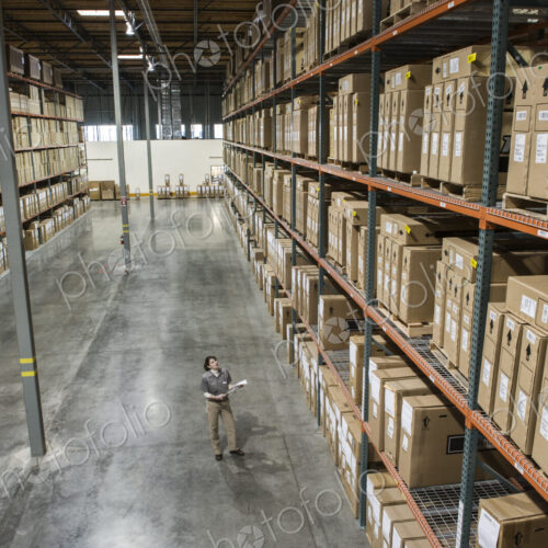 Warehouse worker checking inventory of stock on racks in a distribution warehouse. Warehouse worker checking inventory of stock on racks in a distribution warehouse.