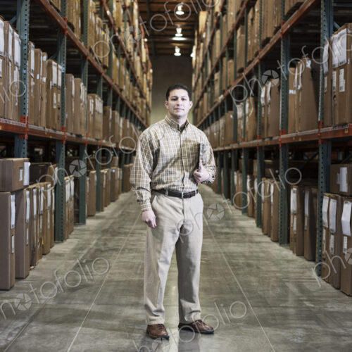 Warehouse worker in an aisle in a distribution warehouse. Warehouse worker in an aisle in a distribution warehouse.
