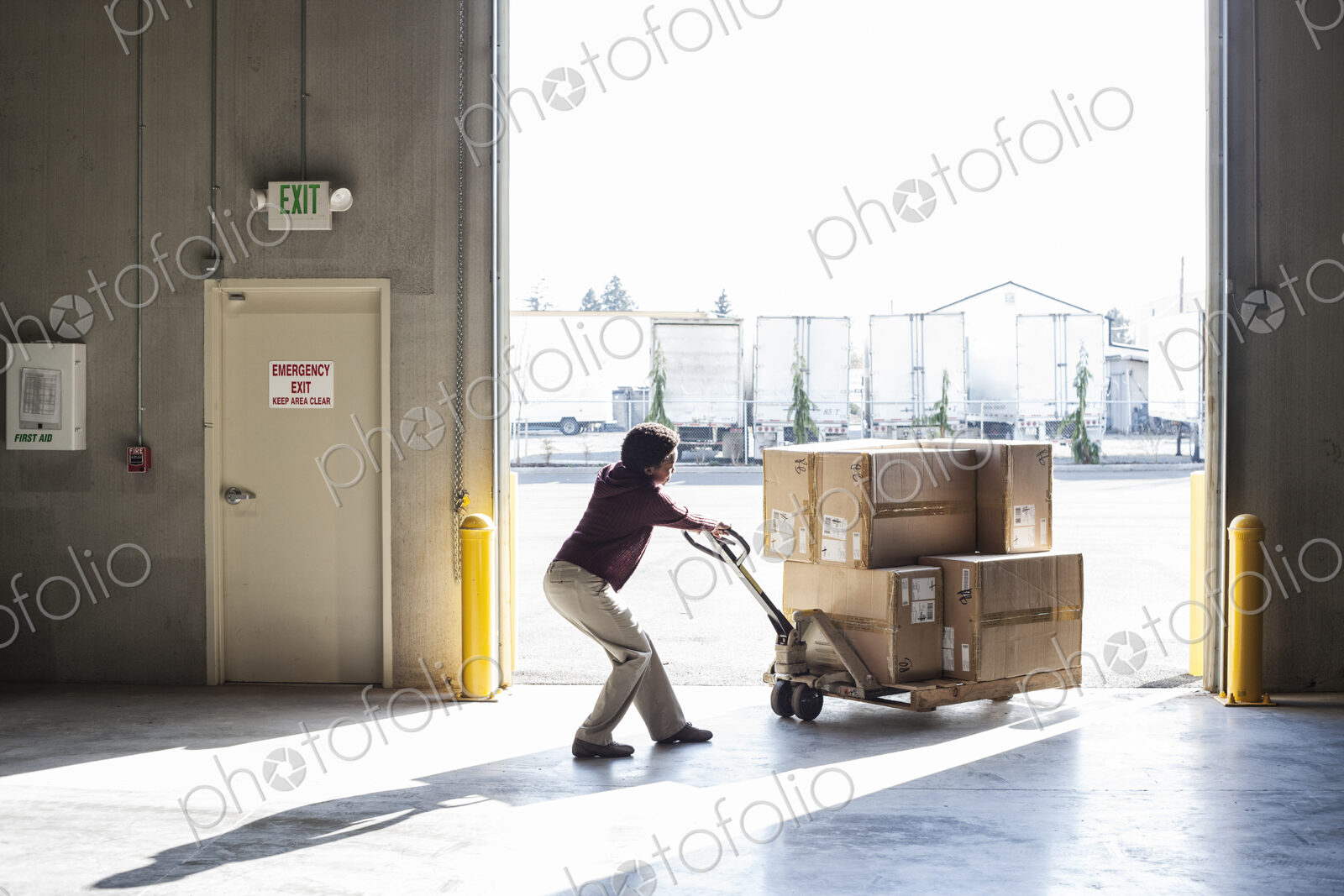 Warehouse worker moving products in cardboard boxes using a manual pallet jack