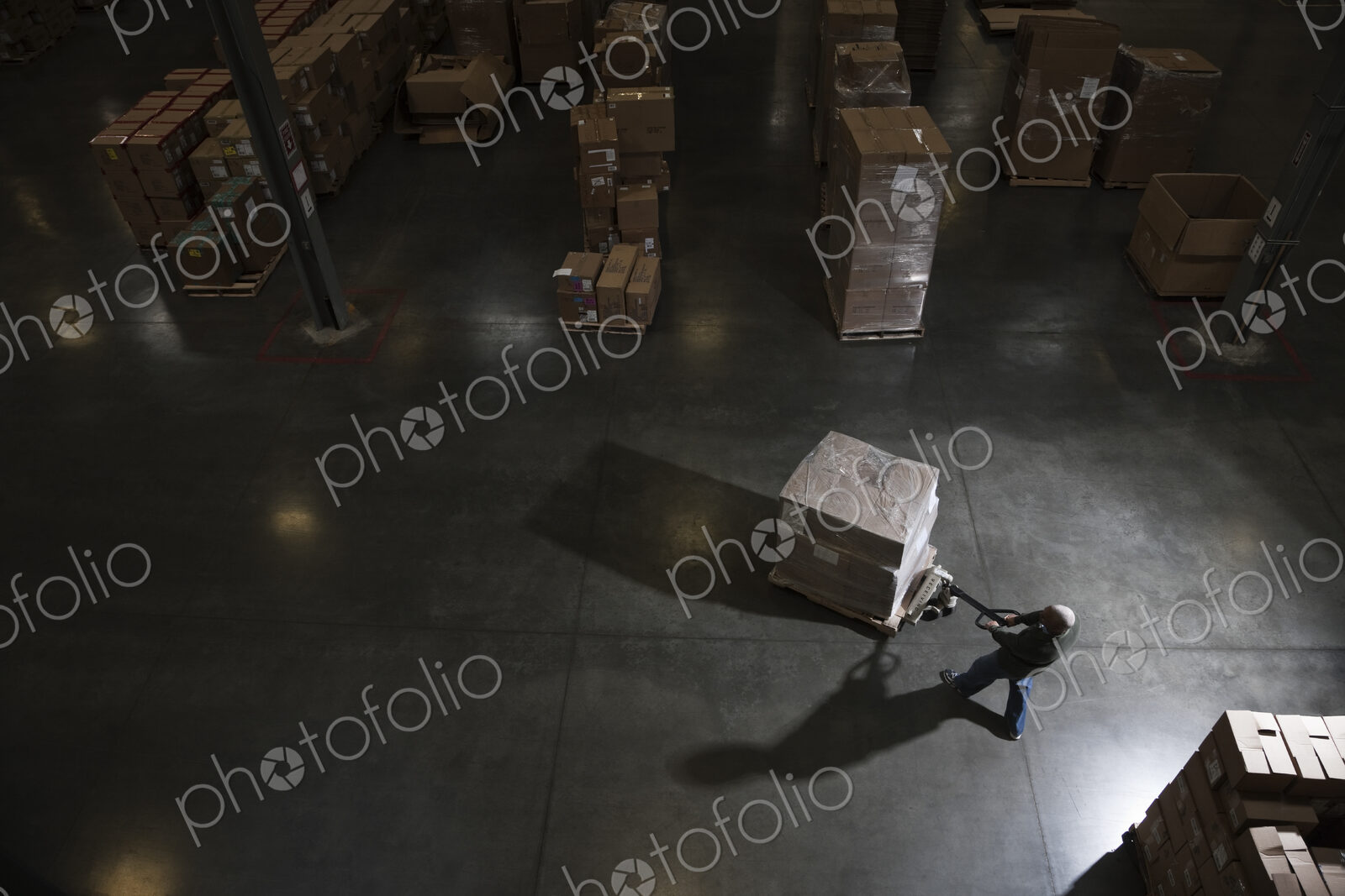 Warehouse worker using a manual pallet jack to move some products in a distribution…
