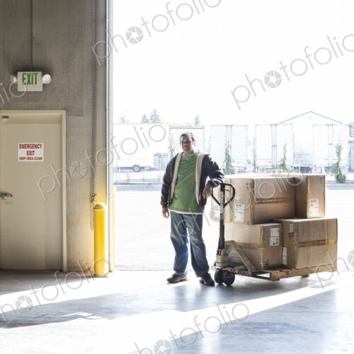 Warehouse worker with manual pallet jack and cardboard boxes in a distribution warehouse. Warehouse worker with manual pallet jack and cardboard boxes in a distribution warehouse.