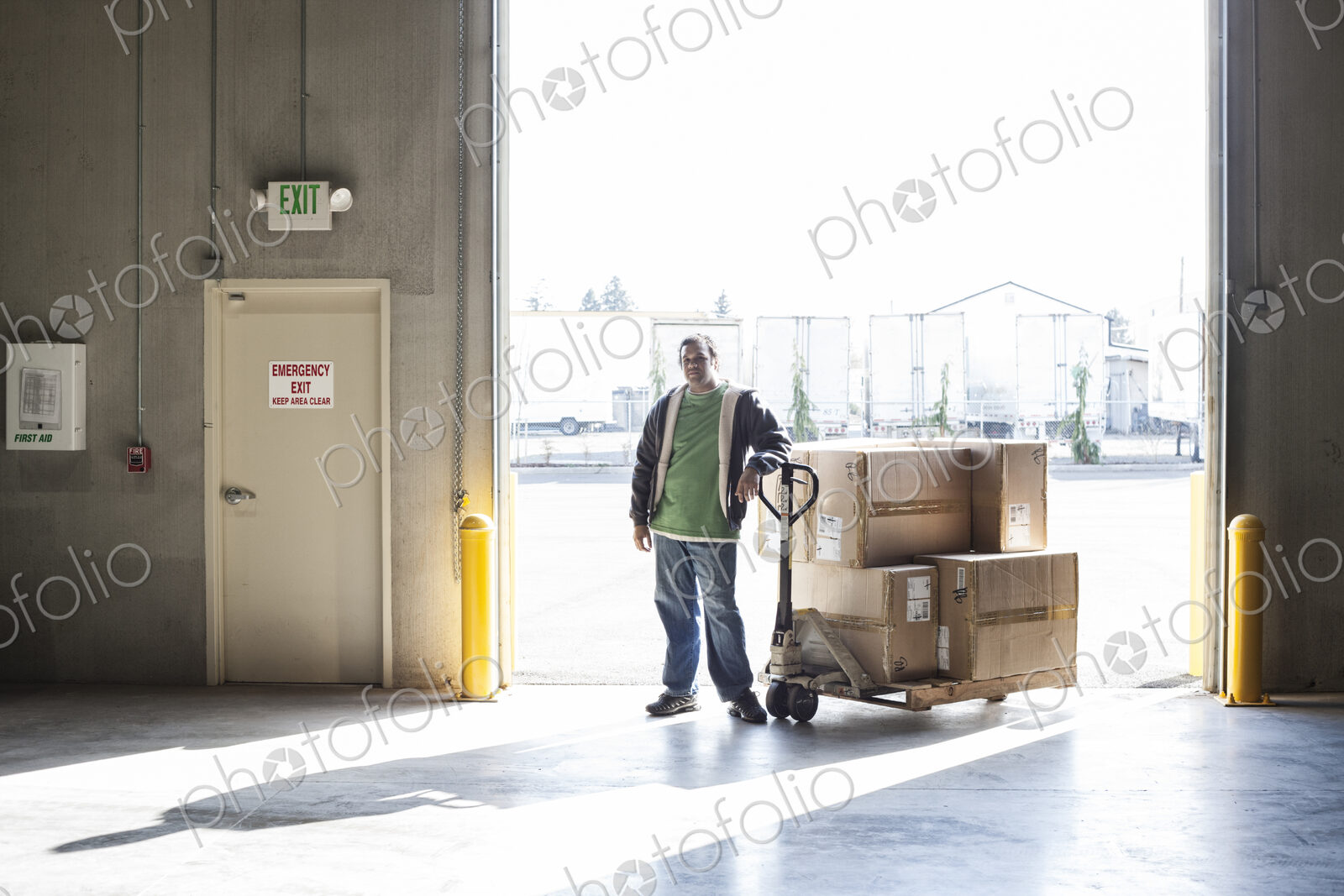 Warehouse worker with manual pallet jack and cardboard boxes in a distribution warehouse.