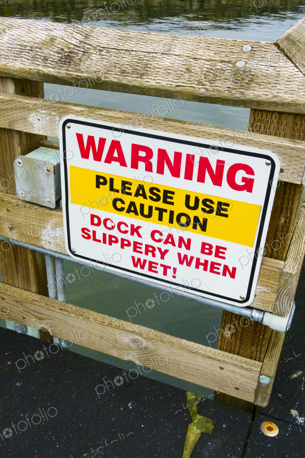 Warning sign on a wooden dock, red lettering, Please Use Caution, Deck can be slippery…