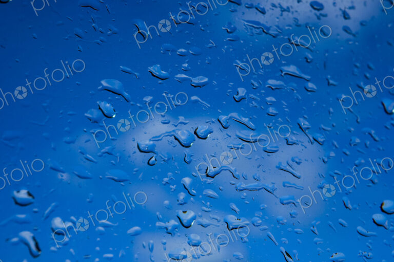 Water droplets on a window, blue background.
