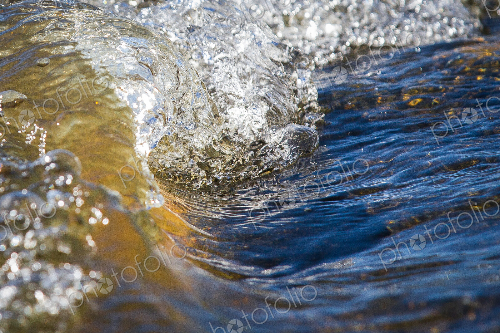 Water from a river makes a small wave with pockets of air, fresh water