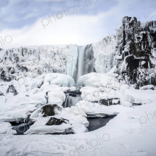 Waterfall pouring over icy cliffs in remote landscape Waterfall pouring over icy cliffs in remote landscape