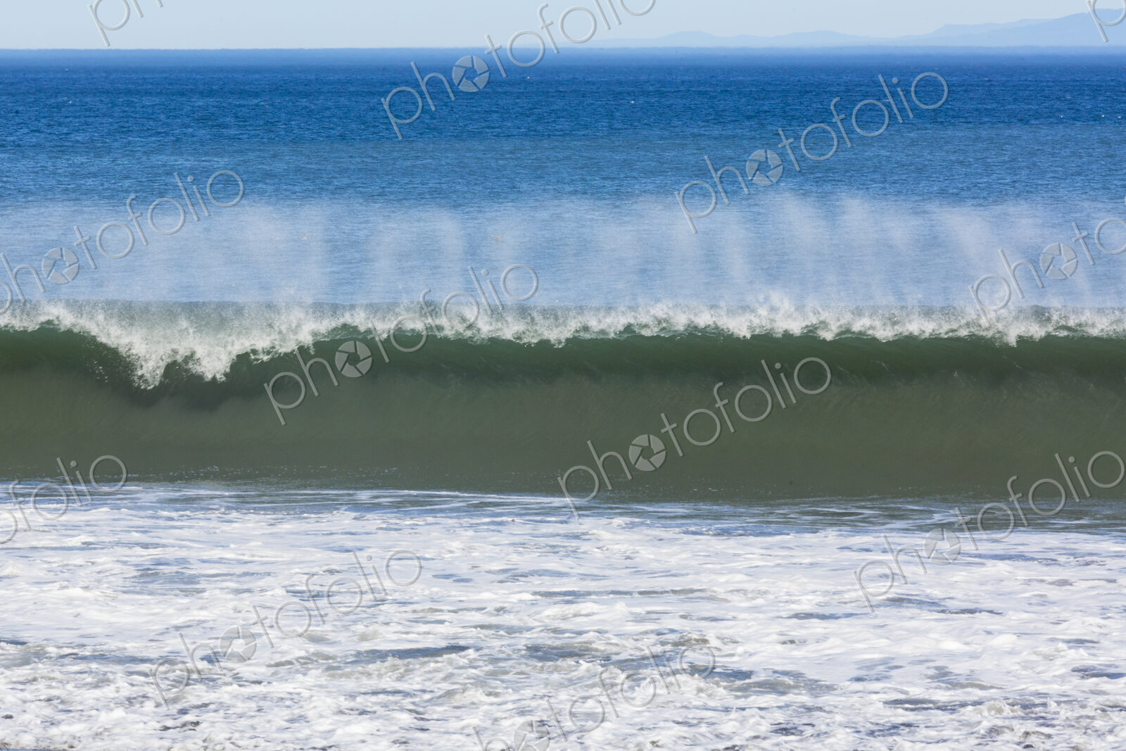 Waves reaching the shore and breaking on the sand.