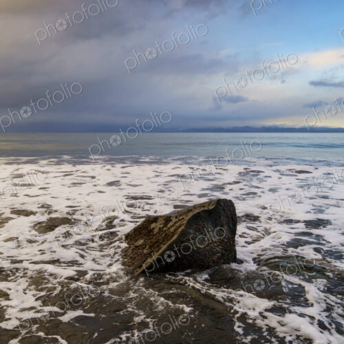 Waves surrounding boulder on beach along the Strait of Juan de Fuca, Port Angeles, WA USA Waves surrounding boulder on beach along the Strait of Juan de Fuca, Port Angeles, WA USA