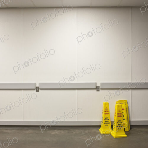 Wet floor warning cones with white wall behind. Wet floor warning cones with white wall behind.