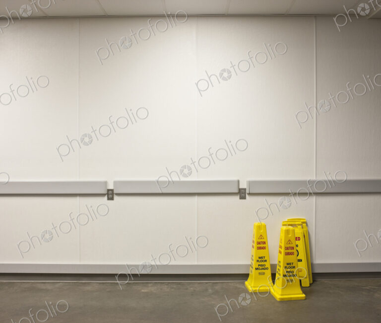 Wet floor warning cones with white wall behind.