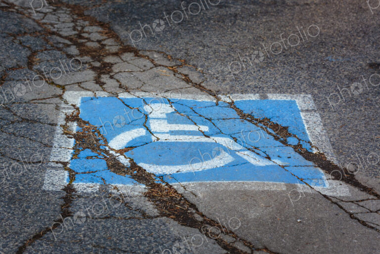 Wheelchair sign, a disabled parking spot, a blue and white sign on a cracked pavement