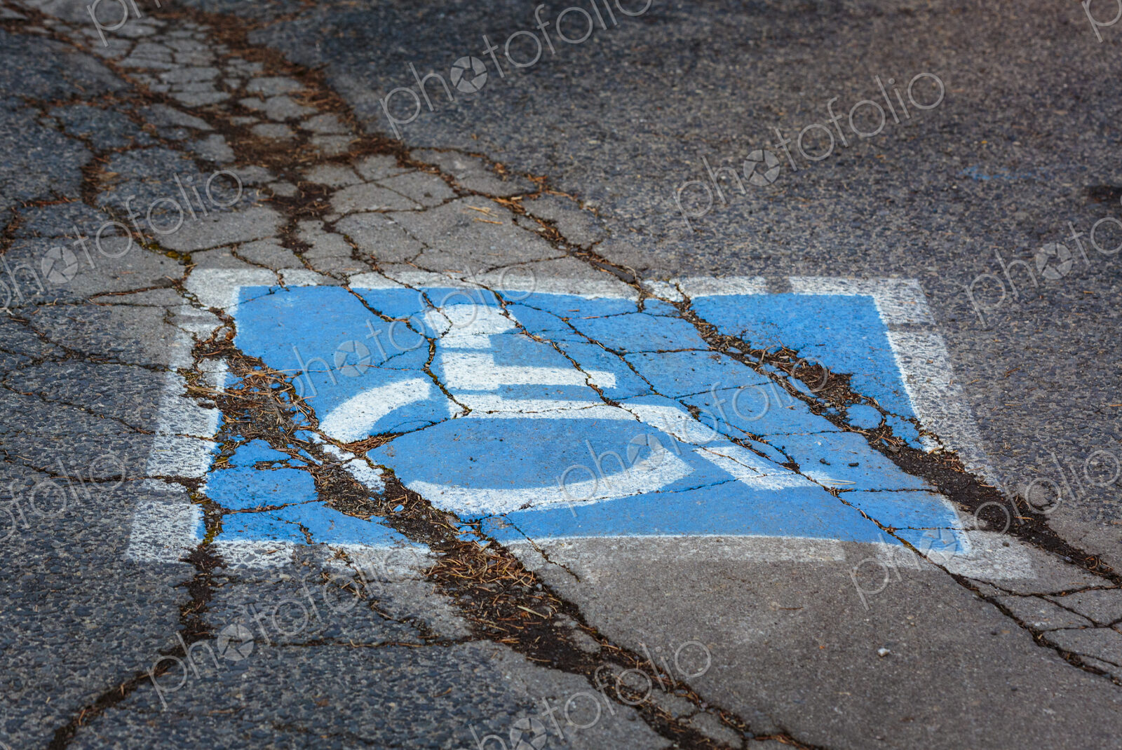 Wheelchair sign, a disabled parking spot, a blue and white sign on a cracked pavement