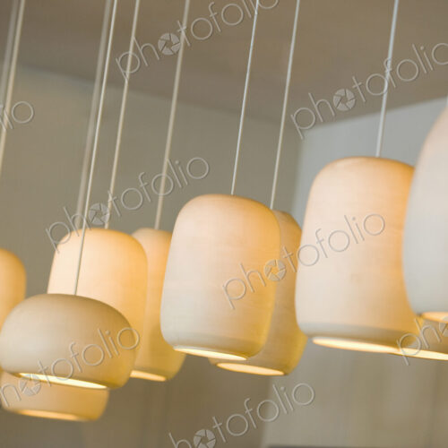 White Lighting Fixtures lit up, hanging in a row White Lighting Fixtures lit up, hanging in a row