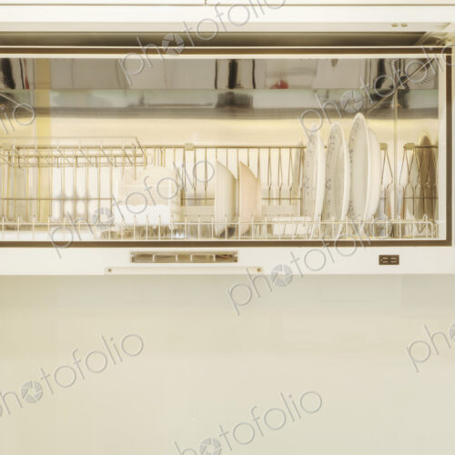 White bowls and dishes in a rack in a kitchen cupboard.