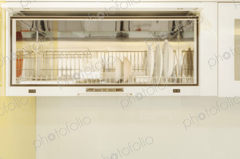 White bowls and dishes in a rack in a kitchen cupboard.