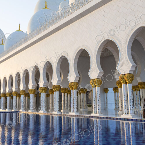 White colonnade of Sheikh Zayed Mosque and blue fountain, Abu Dhabi, United Arab Emirates. White colonnade of Sheikh Zayed Mosque and blue fountain, Abu Dhabi, United Arab Emirates.