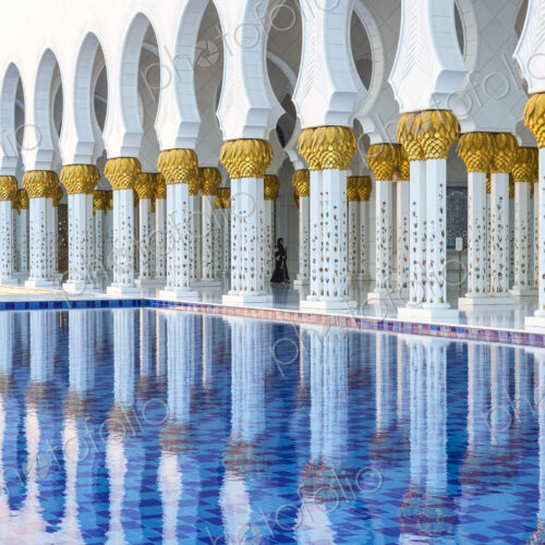 White colonnade of Sheikh Zayed Mosque and blue fountain, Abu Dhabi, United Arab Emirates. White colonnade of Sheikh Zayed Mosque and blue fountain, Abu Dhabi, United Arab Emirates.