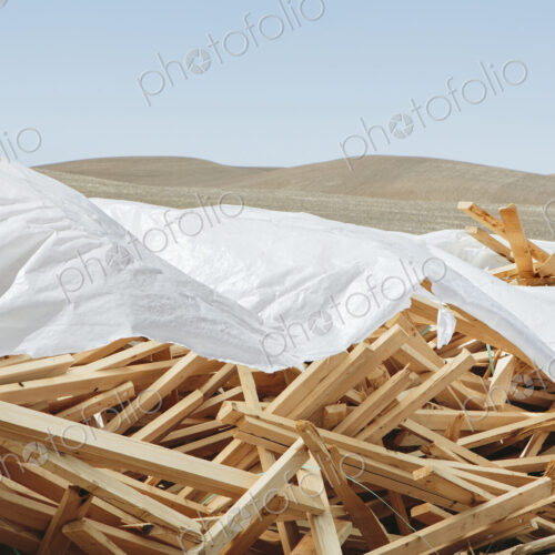 White tarp covering pile of wood 2x4 studs, farmland in background, near Pullman
