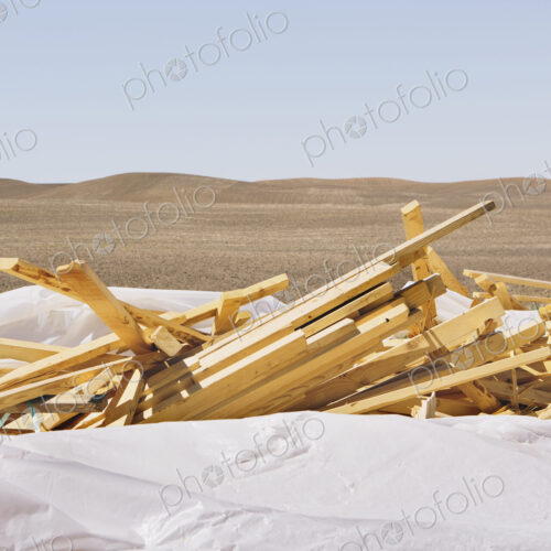 White tarp covering pile of wood 2x4 studs, farmland in background, near Pullman