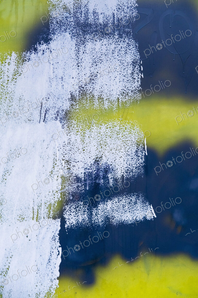 White, yellow and black paint covering graffiti tags on building wall