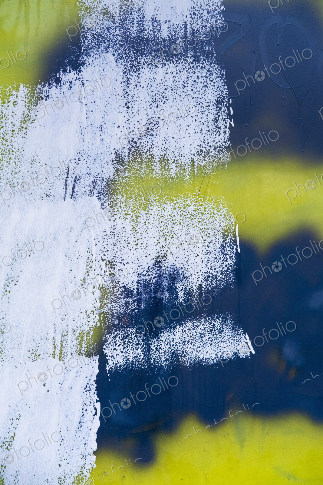 White, yellow and black paint covering graffiti tags on building wall
