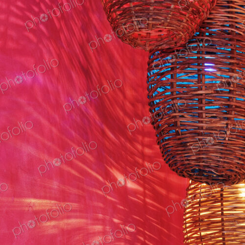 Wicker light fixtures casting shadows on red wall.