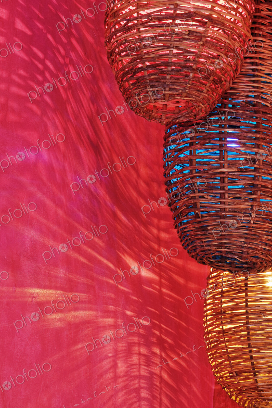 Wicker light fixtures casting shadows on red wall.
