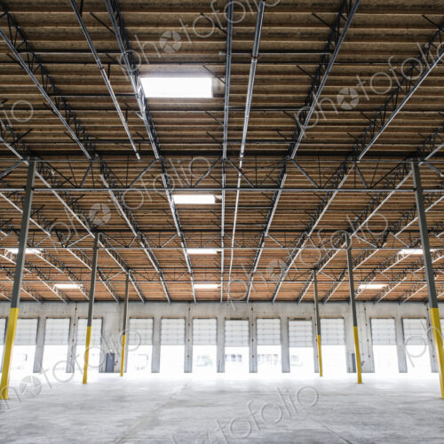 Wide angle interior view of large empty warehouse and loading dock doors Wide angle interior view of large empty warehouse and loading dock doors