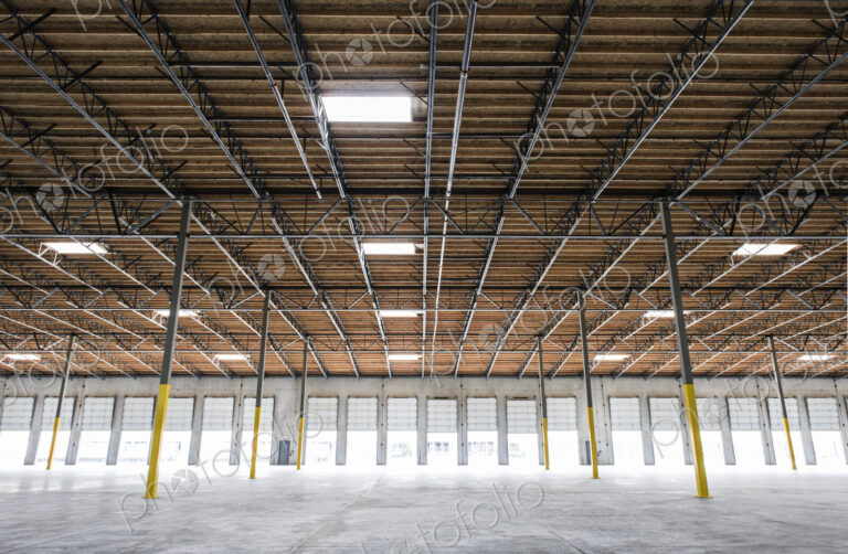 Wide angle interior view of large empty warehouse and loading dock doors