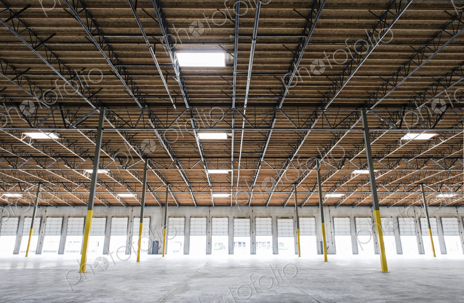 Wide angle interior view of large empty warehouse and loading dock doors