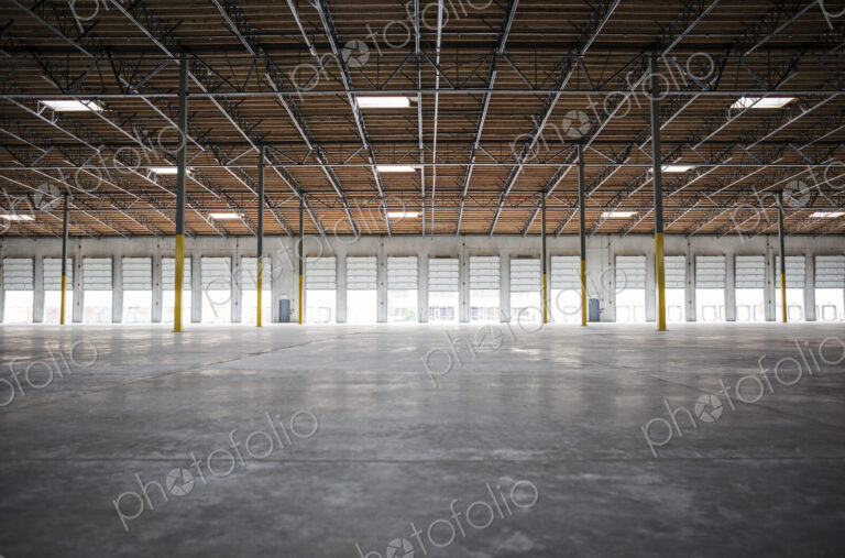 Wide angle interior view of largeempty warehouse and loading dock doors
