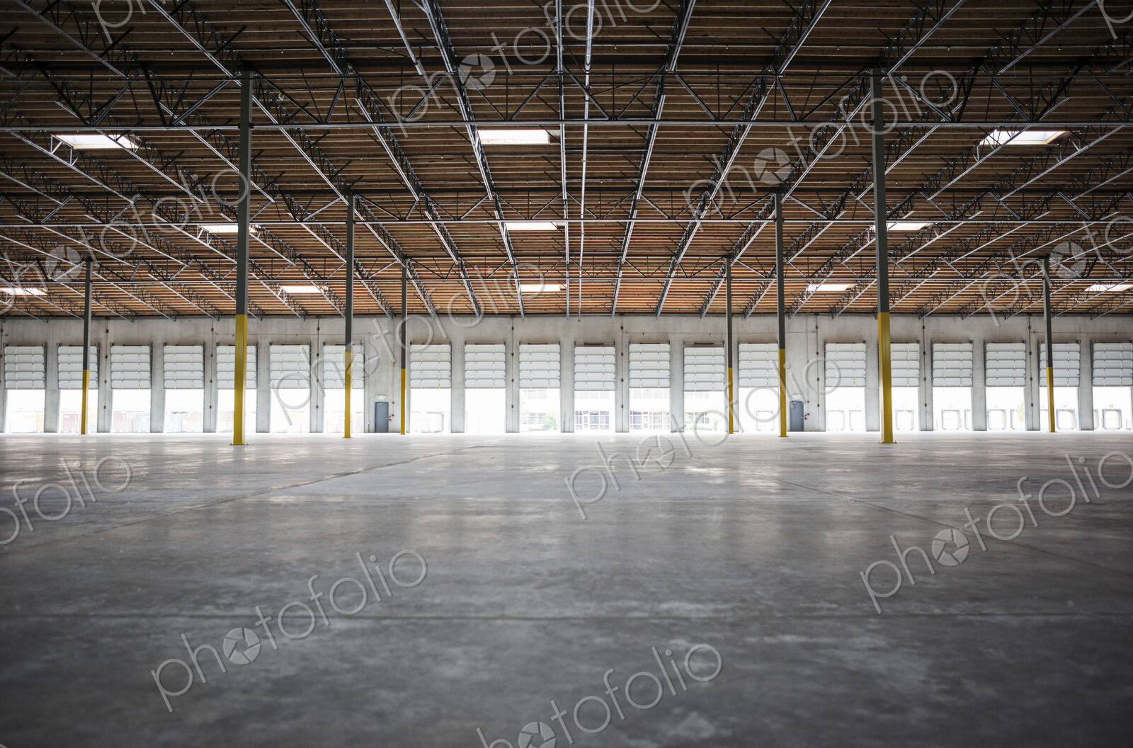 Wide angle interior view of largeempty warehouse and loading dock doors