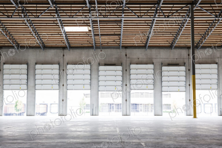 Wide angle interior view of largeempty warehouse and loading dock doors