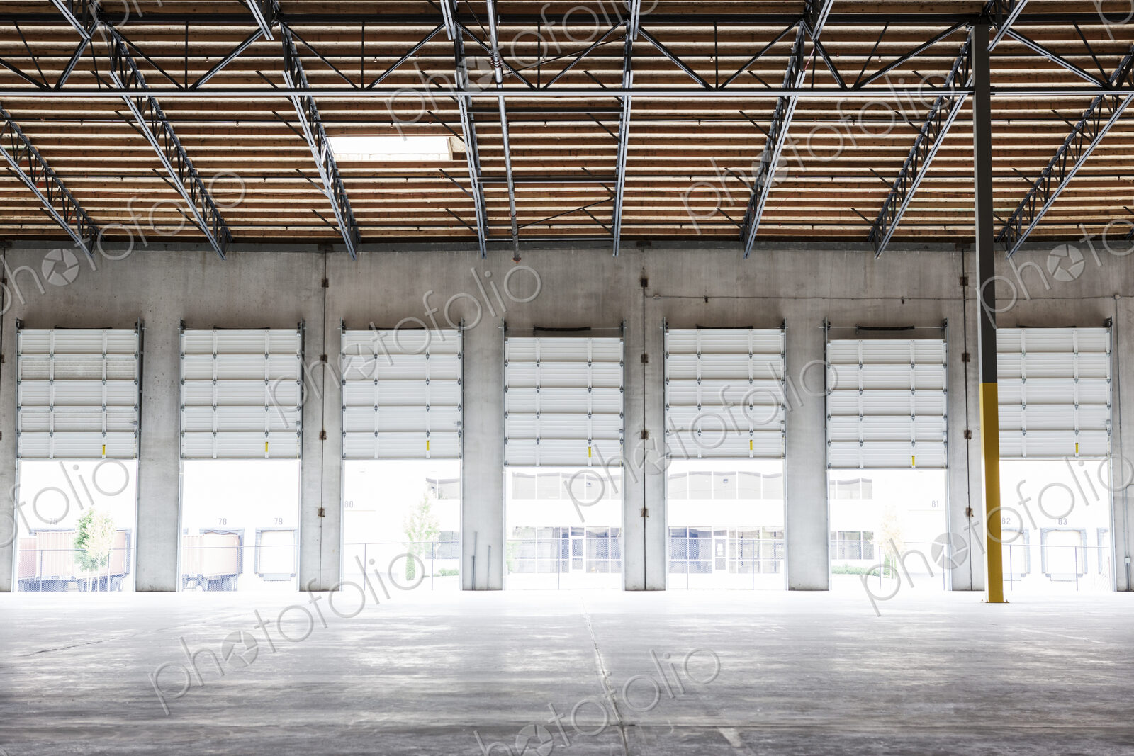 Wide angle interior view of largeempty warehouse and loading dock doors