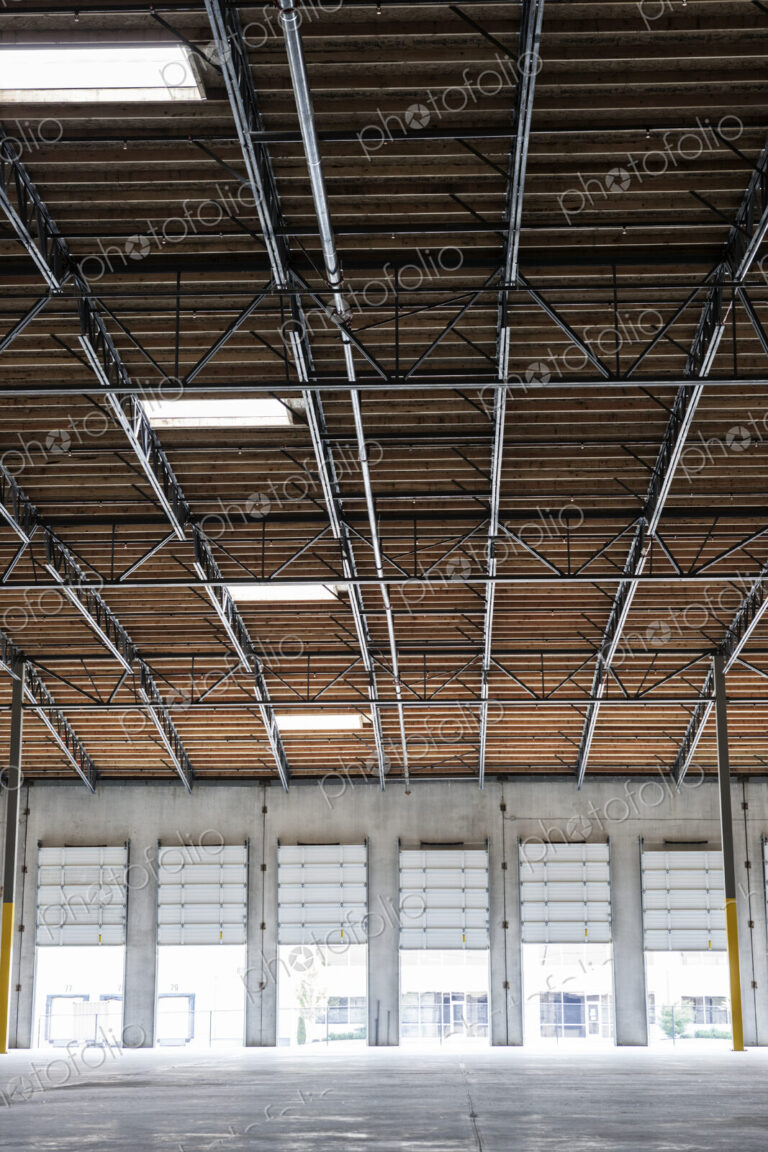 Wide angle interior view of largeempty warehouse and loading dock doors