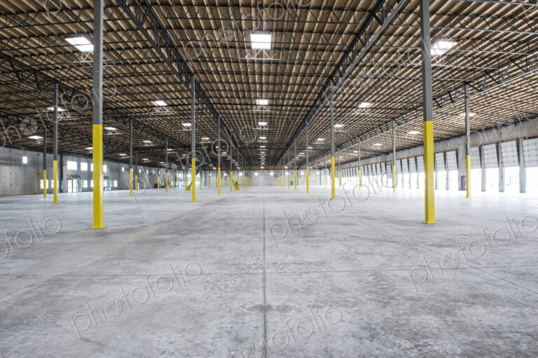 Wide angle interior view of largeempty warehouse and loading dock doors