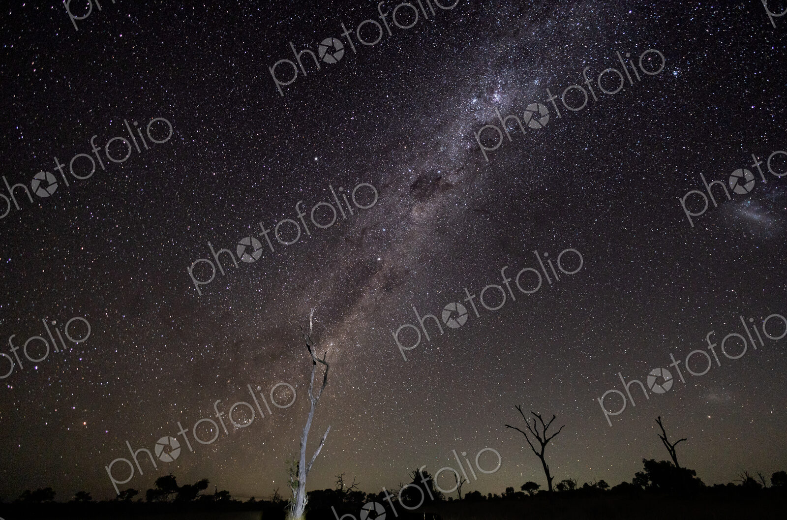 Wide shot of the Milky Way galaxy over a dark horizon and a dark sky.