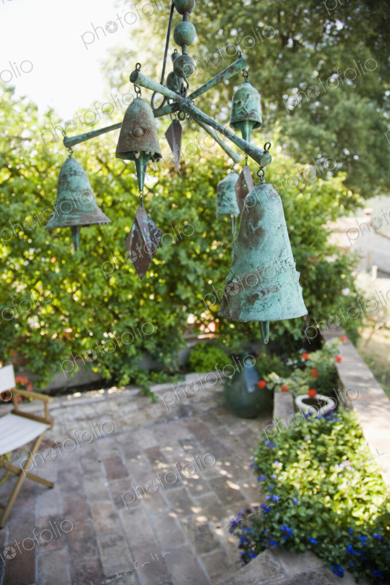 Wind chime or mobile with bronze bells hanging over garden terrace.