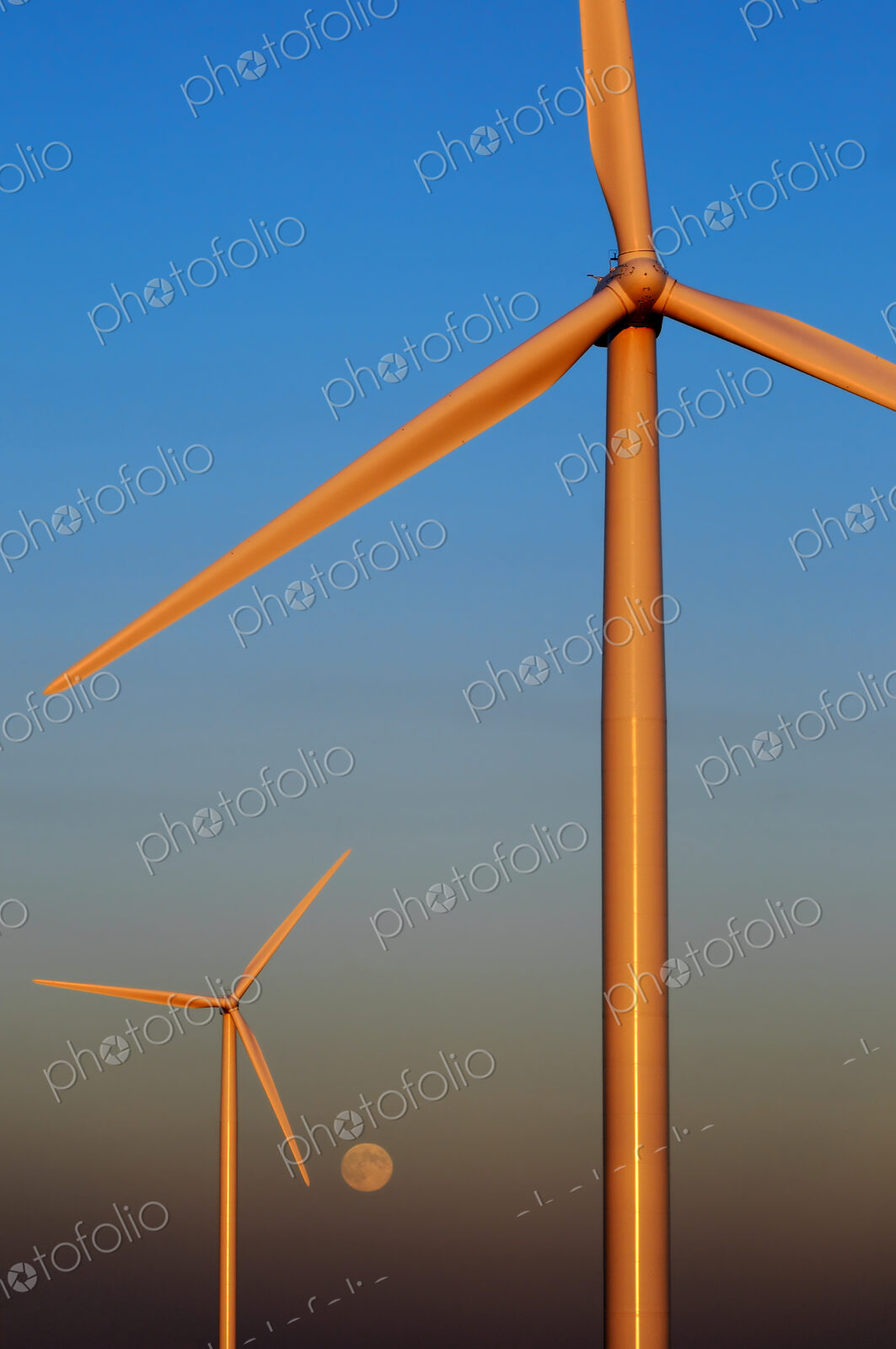 Wind turbines against sunset sky with rising moon