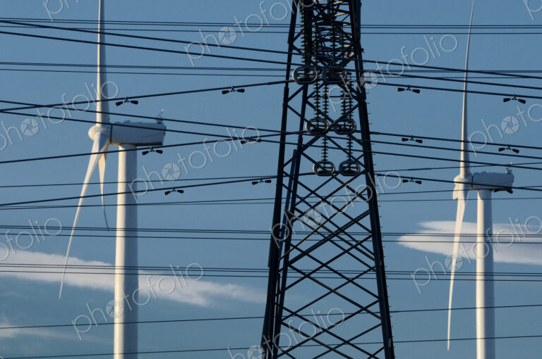 Wind turbines and power lines under blue sky