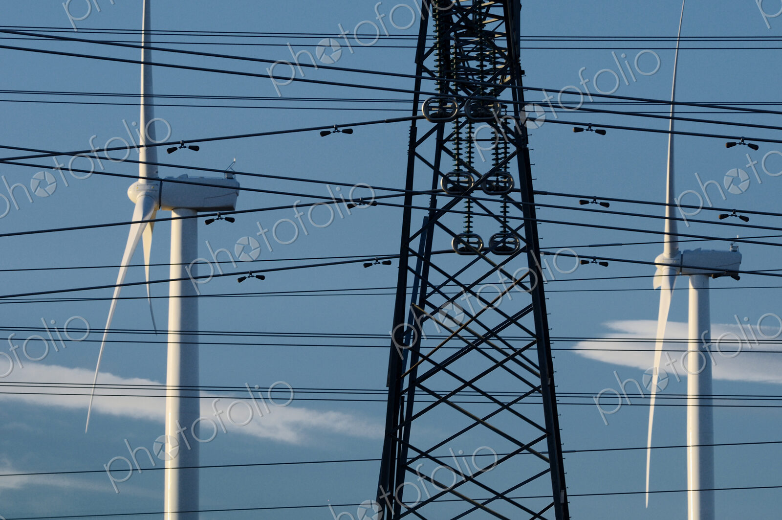 Wind turbines and power lines under blue sky