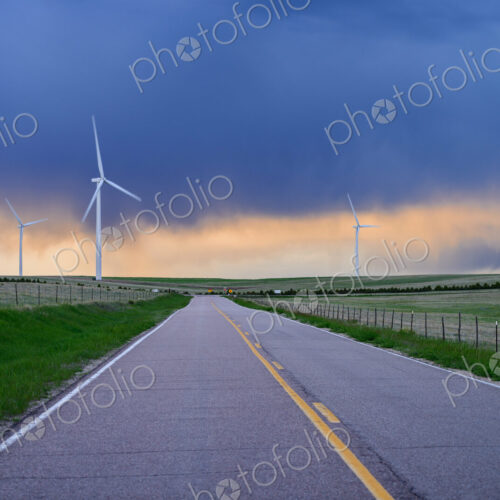 Wind turbines near road at sunset