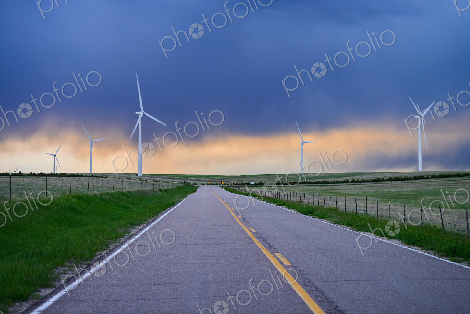 Wind turbines near road at sunset
