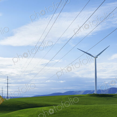Wind turbines on a grassy hilltop, and a road sign warning of a Winding Road. Green… Wind turbines on a grassy hilltop, and a road sign warning of a Winding Road. Green…
