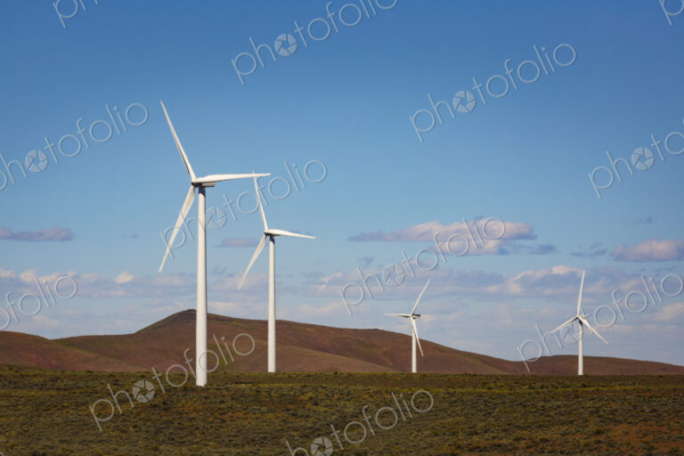 Wind turbines on the rolling hills of Kittikas county in Washington state, tall white…